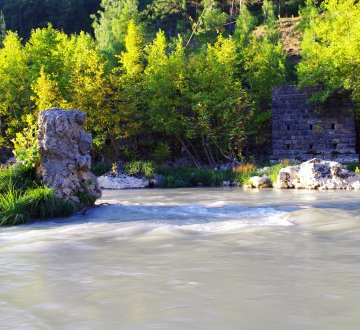 A picture of the ruins of an ancient bridge over a river.